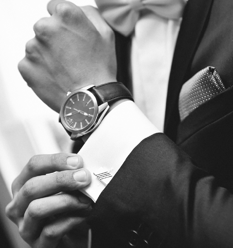 An elegant gentleman in a tuxedo adjusting his sleeve cuff
